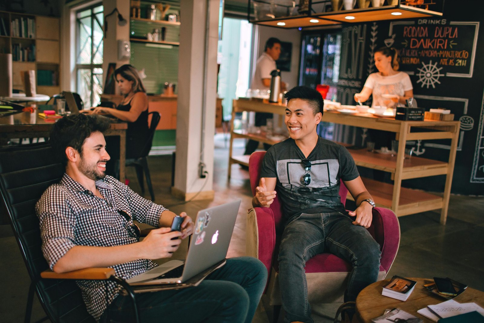 Two men enjoying a relaxed conversation with laptops in a cozy Brazilian café.